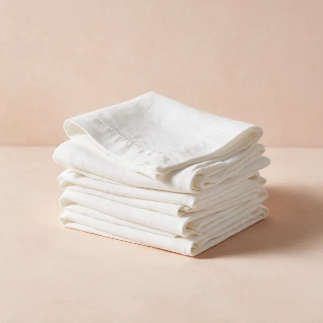 A stack of folded linen napkins in soft white