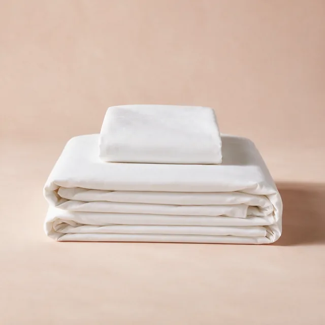 A folded cotton percale sheet set with a pillowcase on top