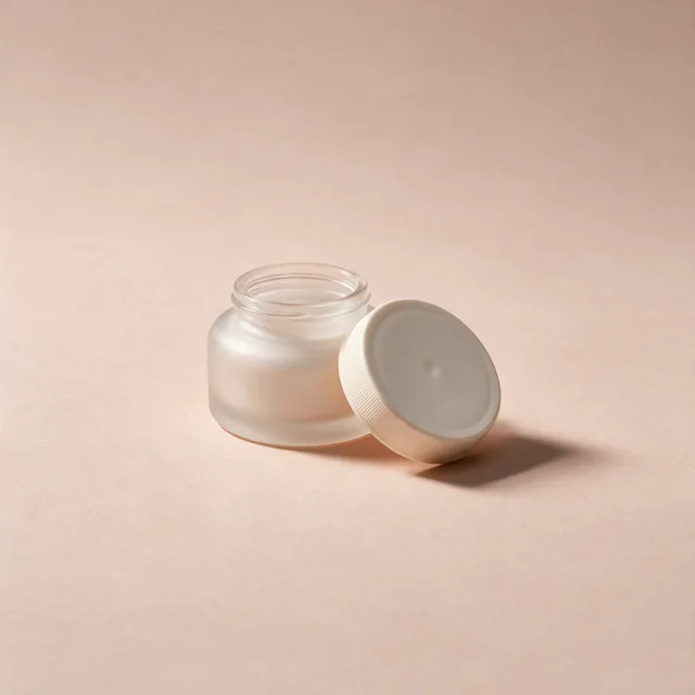 An unlabeled frosted glass jar of facial moisturizer