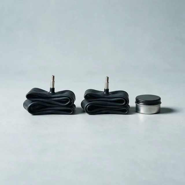 Two folded bicycle inner tubes beside a small tin patch kit