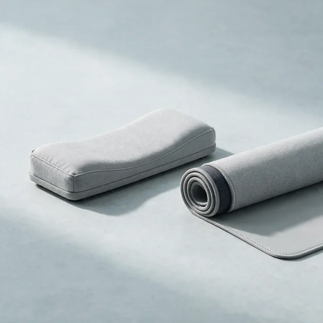A padded keyboard wrist rest beside a rolled desk mat