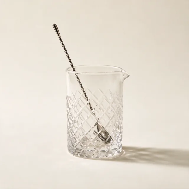 A cut-glass mixing glass with a twisted bar spoon