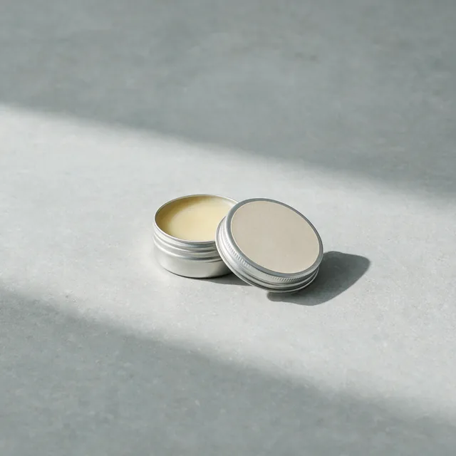A small tin of anti-chafe balm with the lid beside it