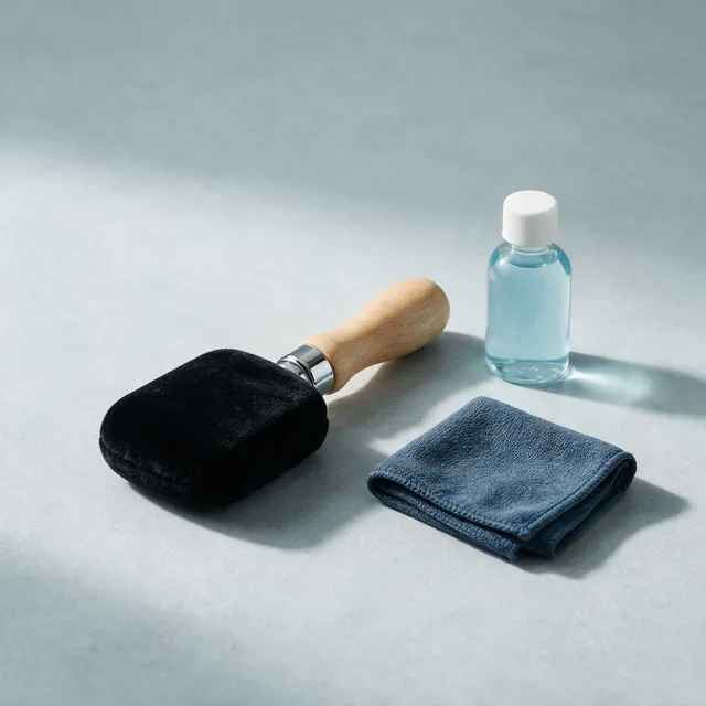 A velvet record brush beside a bottle of cleaning fluid and a cloth