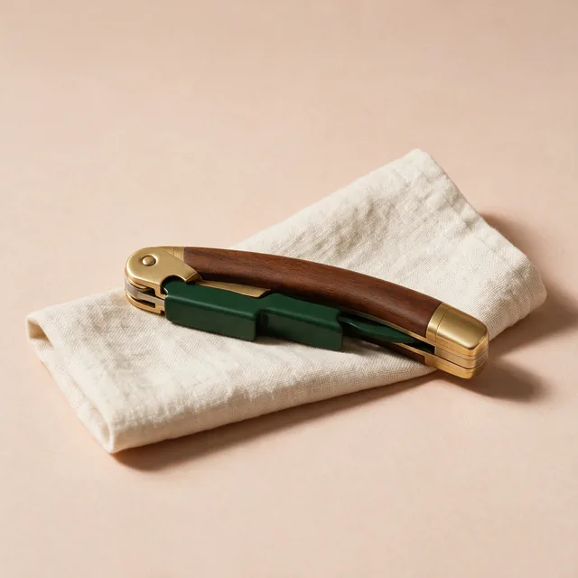 A waiter's corkscrew folded closed on a linen napkin