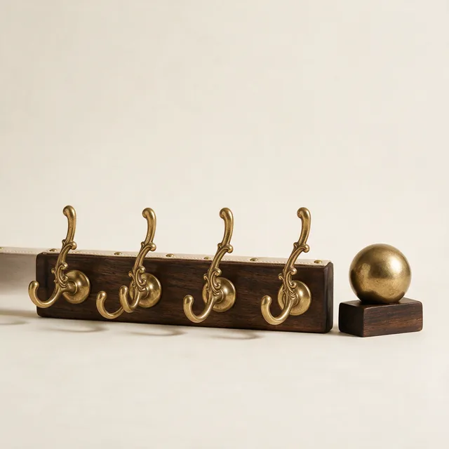 Four brass wall hooks on a wooden rail beside a doorstop