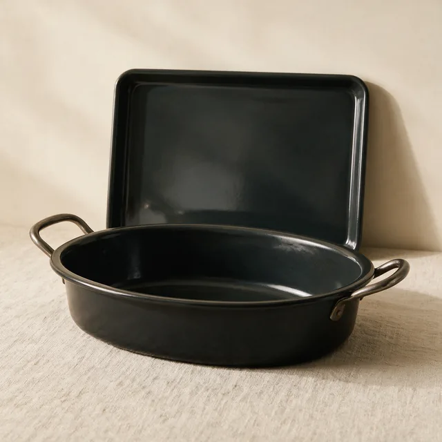 A heavy roasting pan with a baking sheet behind it