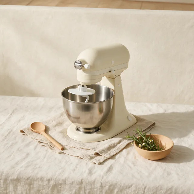 A cream stand mixer with its bowl and beater fitted