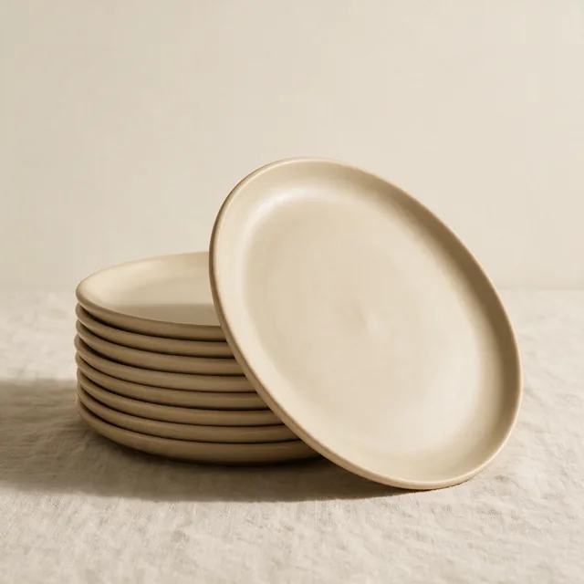 A stack of plain stoneware dinner plates in oatmeal